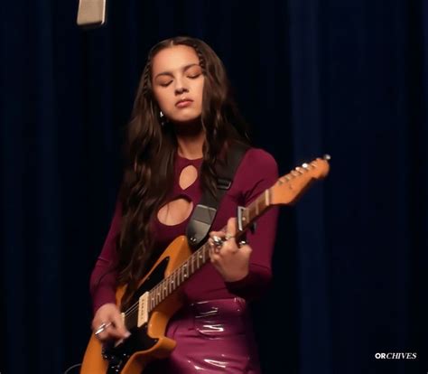 a woman in a purple dress playing an electric guitar