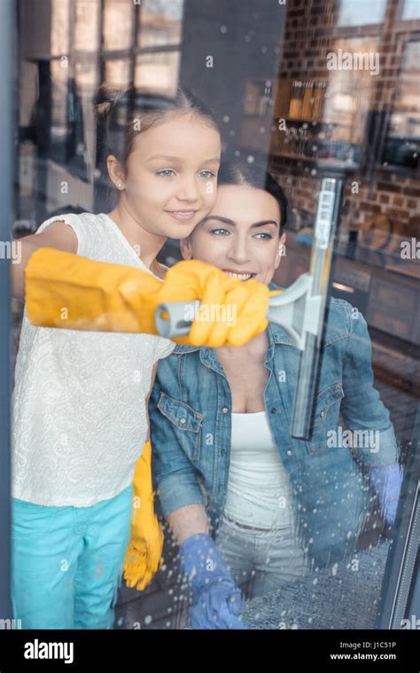 Happy mother and daughter in protective gloves cleaning window together Stock Photo - Alamy