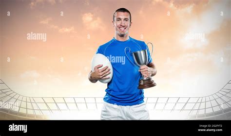 Composition of male rugby player celebrating victory, holding trophy at ...