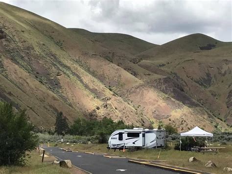 an rv parked on the side of a road in front of some hills and trees