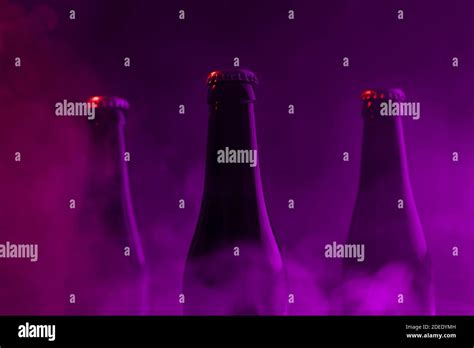 Glass bottles of beer on purple foggy smoke dark background.Abstract background , drink, party ...