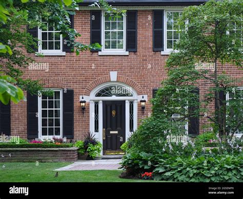 Traditional brick two story house with black shutters Stock Photo - Alamy