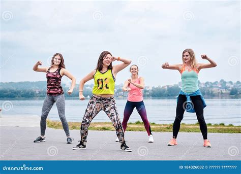 A Group of Young Women, Wearing Colorful Sports Outfits, Doing Zumba Exercises Outside by City ...