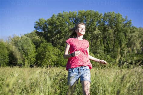 Happy teenage girl running on a meadow stock photo