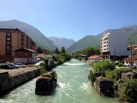 a river running through a small town surrounded by mountains and buildings on either side of it