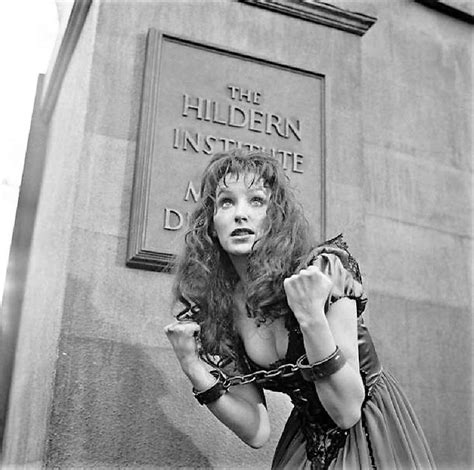 a woman in a dress is chained to the side of a building