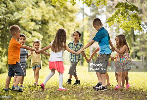 Group Of Small Kids Playing Ringaroundtherosy In The Park Stock Photo & More Pictures of Bonding ...