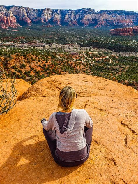 a woman sitting on top of a rock looking out over the valley and canyons