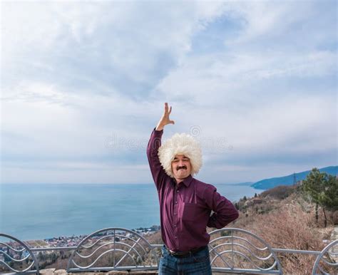 Tourist in Traditional Caucasian Hat Made of White Sheepskin Dancing Lezginka on Background of ...