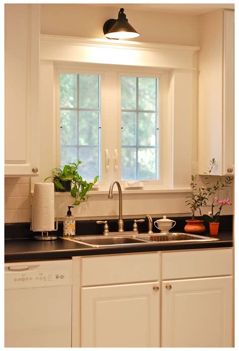 a kitchen with white cabinets and black counter tops next to a dishwasher under a window