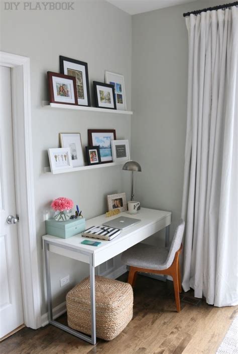 a white desk sitting under a window next to a chair and pictures on the wall