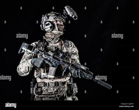 Studio portrait of a special forces member wearing night vision goggles, isolated on black ...