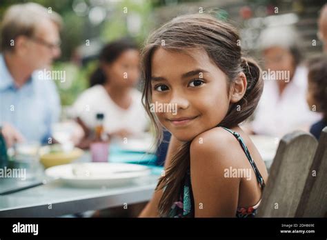 Portrait of smiling girl sitting with family at outdoor dining table Stock Photo - Alamy