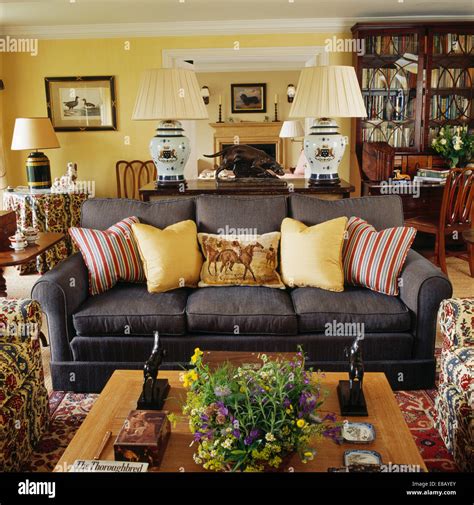 Pale yellow and striped cushions on dark grey sofa in yellow country ...