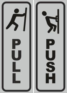 two black and white signs with the words push and a man climbing on one pole