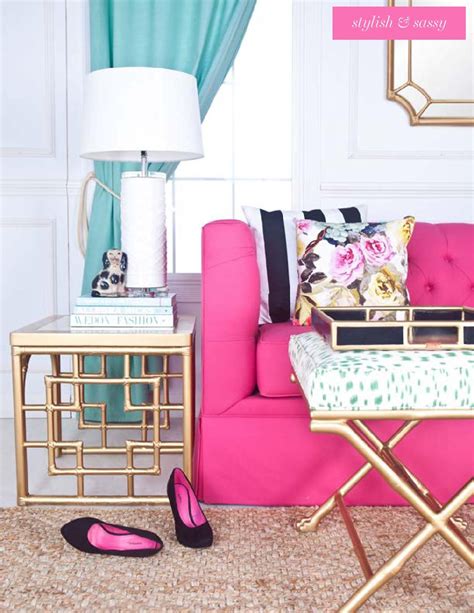 a living room with pink couch, gold side table and black and white accessories on the floor