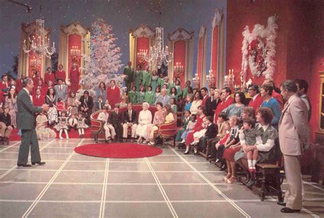 a group of people sitting on chairs in front of a stage with a red carpet