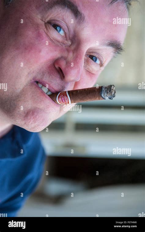 A man enjoys a cigar and makes funny faces whilst smoking Stock Photo ...