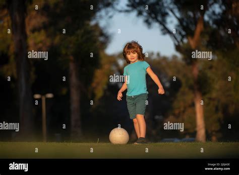 Little kid boy playing football in the field with soccer ball. Concept ...