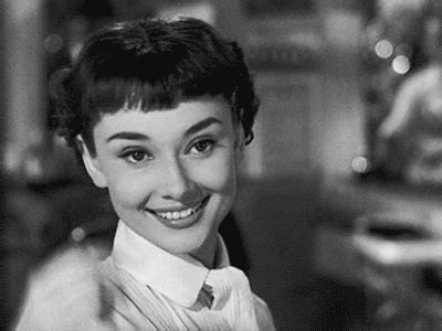 an old black and white photo of a woman with short hair smiling at the camera