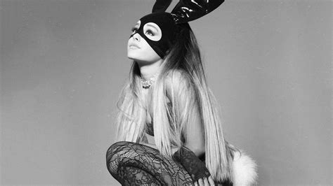 a woman with long hair wearing a bunny mask and stockings, sitting on a stool