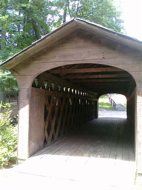 a wooden covered walkway with trees in the background