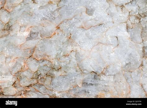 Light rough surface of marble with red stains. Closeup of raw stone ...