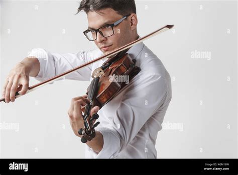 Confident young man playing violin against white background Stock Photo - Alamy