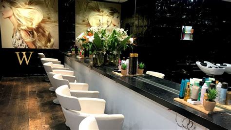 there are many white chairs lined up at the hairdresser's salon counter