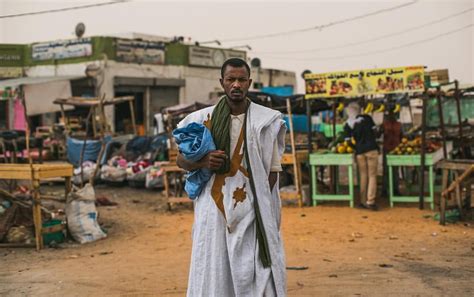 a man standing in the middle of a dirt road with bags on his back and ...