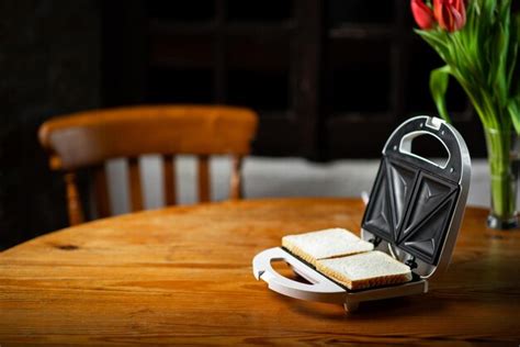 Premium Photo | Sandwich maker with bread toast on wooden table ...