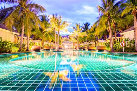 Swimming pool with palm trees in resort hotel at night | Free Photo