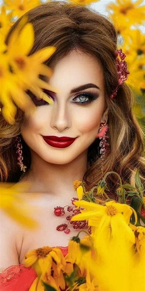 a woman with long hair and red lipstick is surrounded by yellow flowers ...