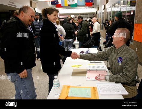 Republican Party precinct leader Troy Mapes (R) greets Jeff and Jennifer Mertz (C) at a caucus ...