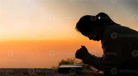 Silhouette of woman kneeling down praying for worship God at sky ...