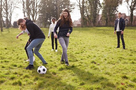 Group of teenagers playing soccer in park together - Stock Photo - Dissolve