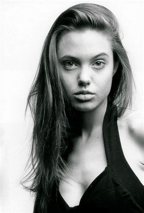 a black and white photo of a woman with long hair, wearing a halter top