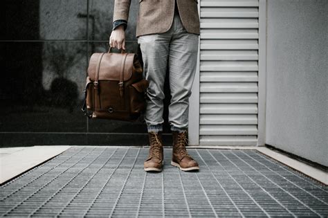 Photo of Man in Brown Blazer,Gray Pants, and Brown Boots Holding Brown Leather Bag Standing ...