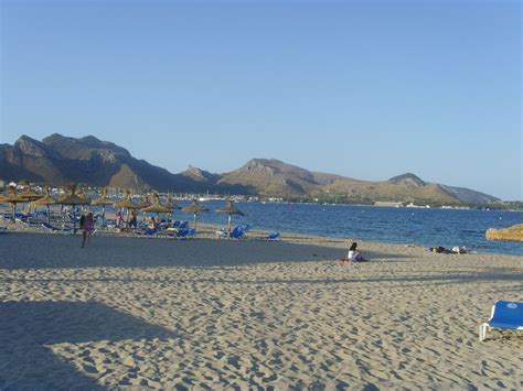 people are on the beach with umbrellas and lounge chairs in the sand by the water