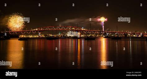 Auckland Sky Tower fireworks for New Year celebration with Harbour bridge illuminated in red ...