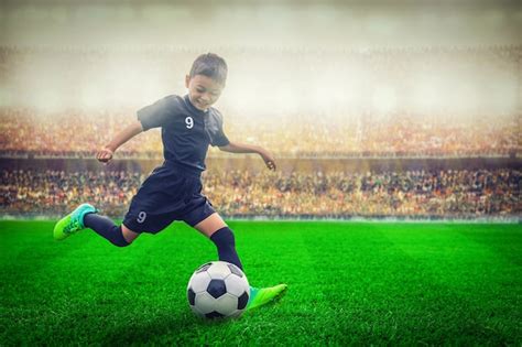 Premium Photo | Asian soccer kid kicking football in the stadium