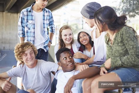 Teenage friends hanging out talking at skate park — togetherness, asian ...