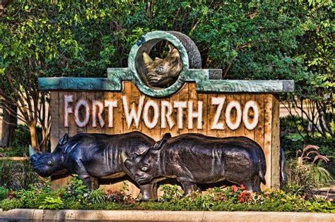 the entrance sign to fort worth zoo with two rhinos in it's habitat