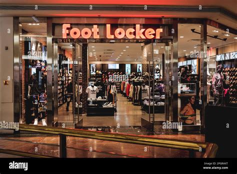 A photo features the exterior of a Footlocker store, with its iconic black and white logo ...