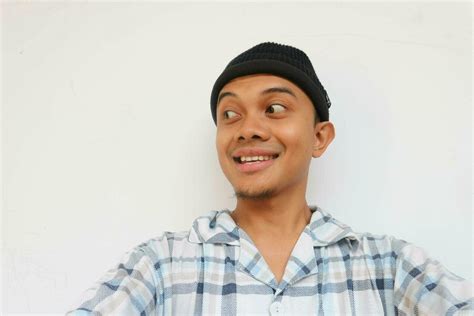 Smiling adult man wearing pajamas and beanie cap glancing to sideways to look something ...