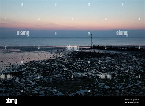 Sea groynes and reflected light over Hunstanton beach at sunset Stock ...