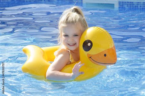 Little girl playing with yellow duck swimming inflatable pool seat ...