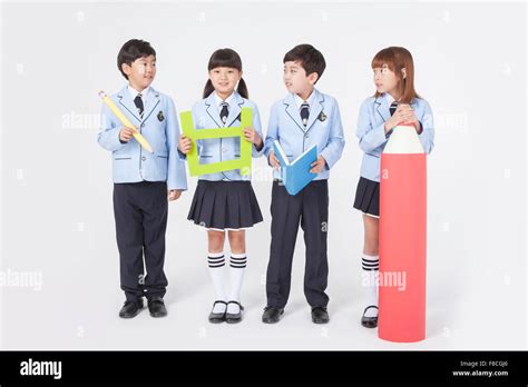 Four elementary school students in school uniforms standing together holding a pencil, a Korean ...