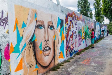 BERLIN, GERMANY - AUGUST 6, 2017: Graffiti Artists Painting on a Section of Berlin Wall in ...