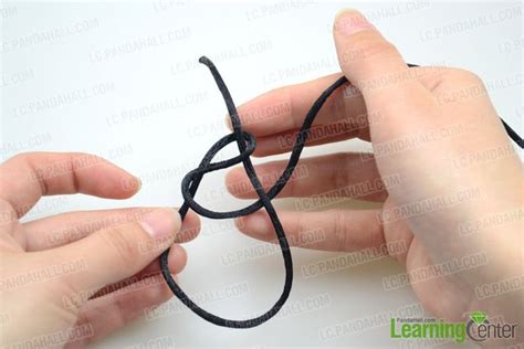 two hands are working on an object with black thread and yarn in the ...